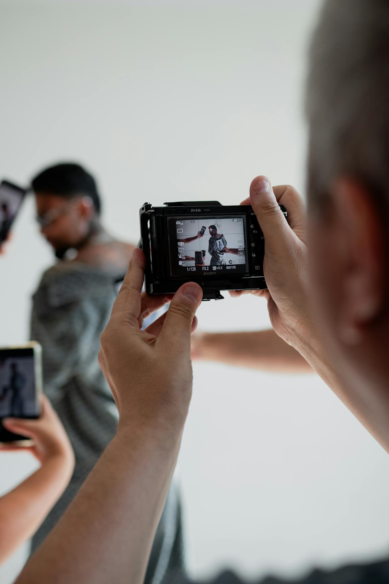 Photographer focuses on a model in a fashion studio, highlighting professional photography setup.
