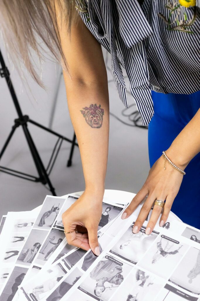 Arm with tattoo sorting black and white photos in a studio setting.