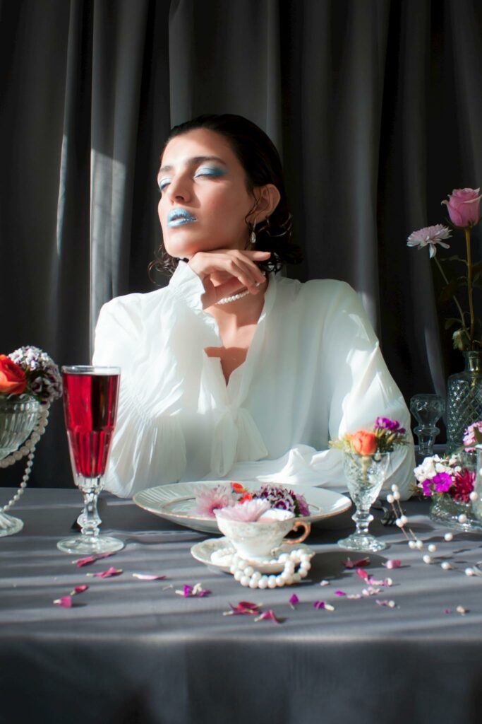 Woman in white at a stylish table with flowers and a red drink.