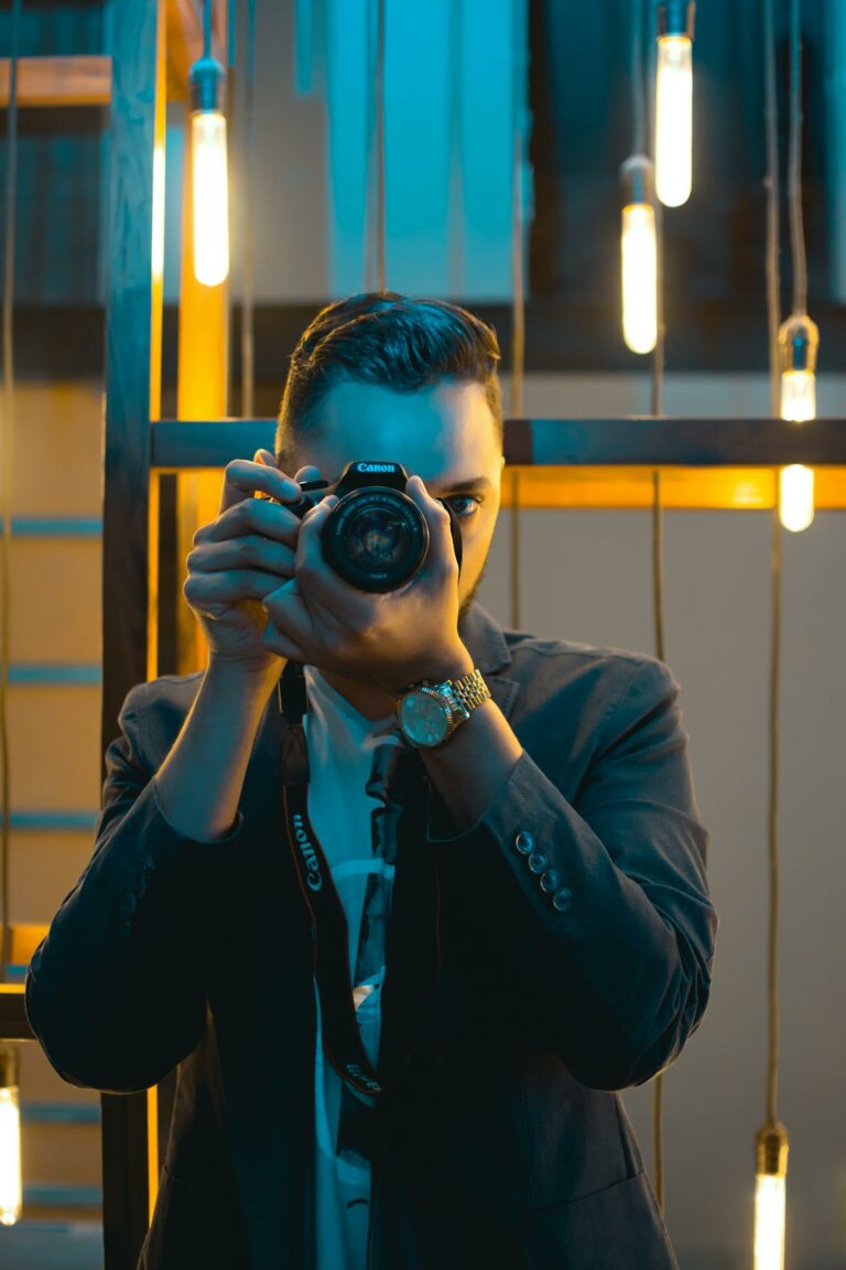 A stylish photographer in a modern setting capturing a shot with ambient lighting.
