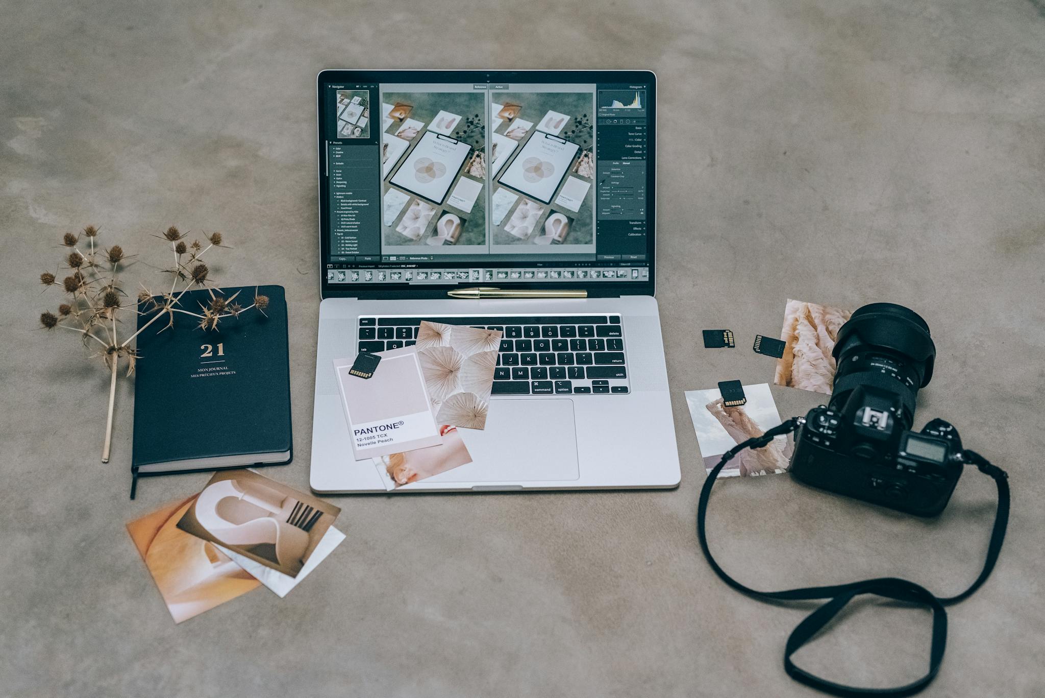 Overhead view of a photographer's workspace with a laptop, camera, and design prints.